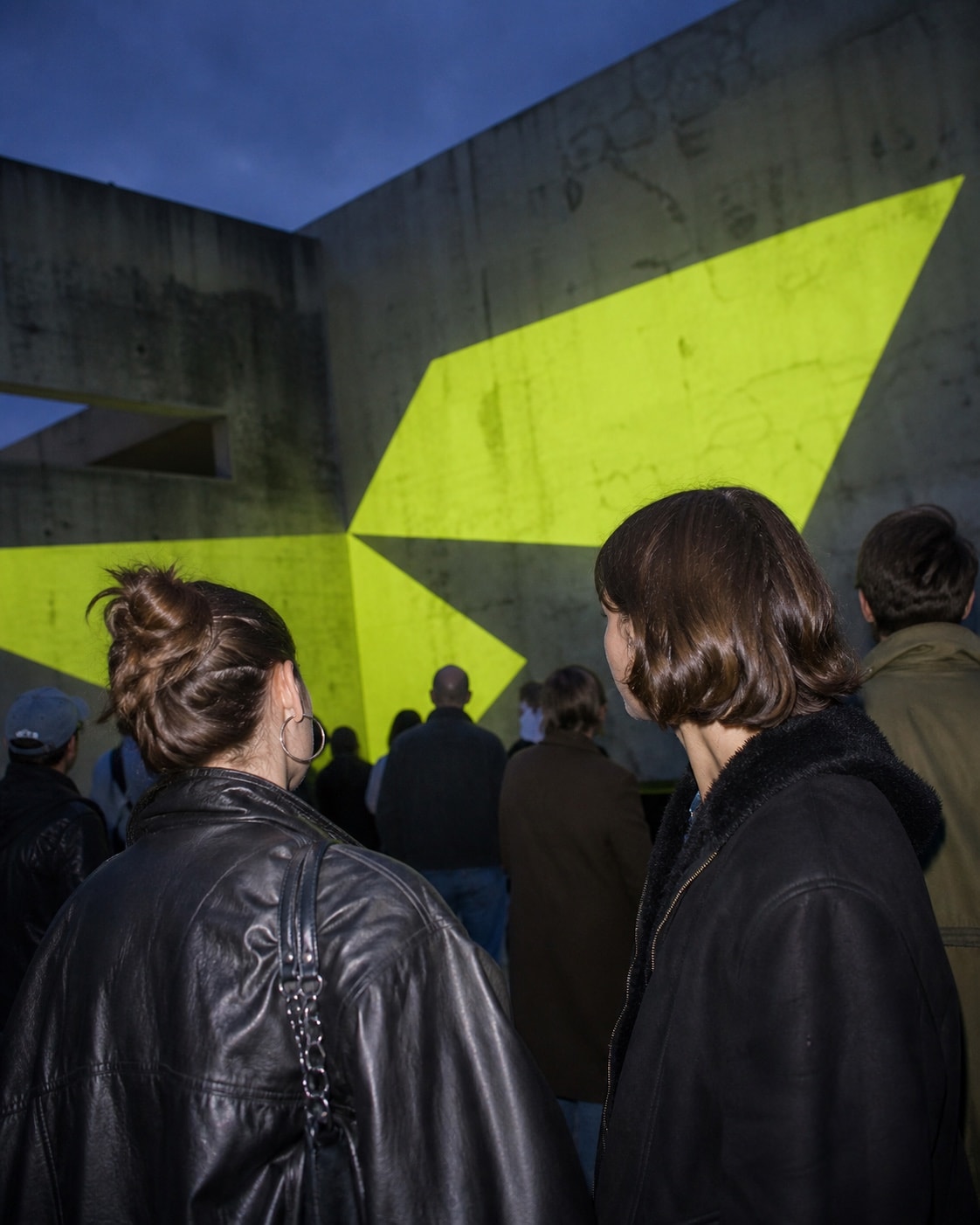 Visitors exploring an independent light installation in a city courtyard